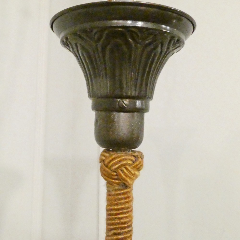 An Art Deco bronze chandelier featuring carved alabaster shade cups suspended from a corded stem with decorative tassel detail. View XV