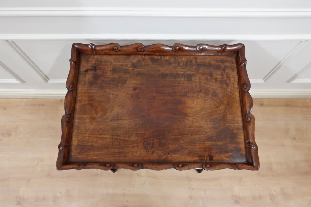 A Regency mahogany side table featuring a scalloped gallery tray top resting on turned end-supports with a central stretcher and splayed legs. View II