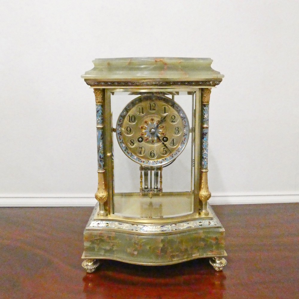 An antique French four-glass mantel clock featuring green onyx bases, champleve enamel columns, and a visible brass movement.