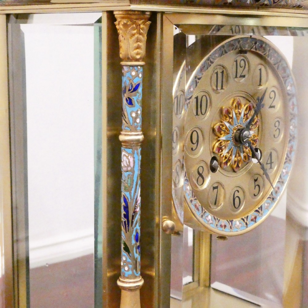 An antique French four-glass mantel clock featuring green onyx bases, champleve enamel columns, and a visible brass movement. View VI