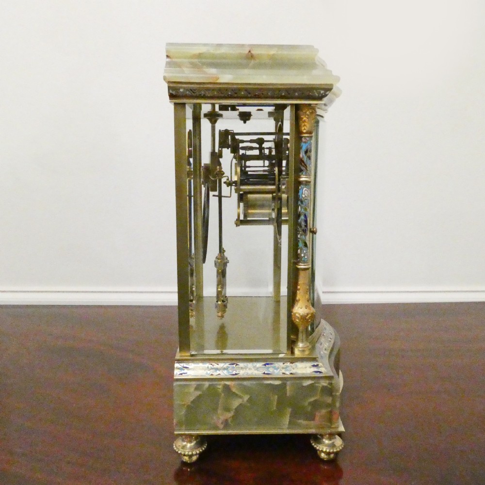 An antique French four-glass mantel clock featuring green onyx bases, champleve enamel columns, and a visible brass movement. View IX