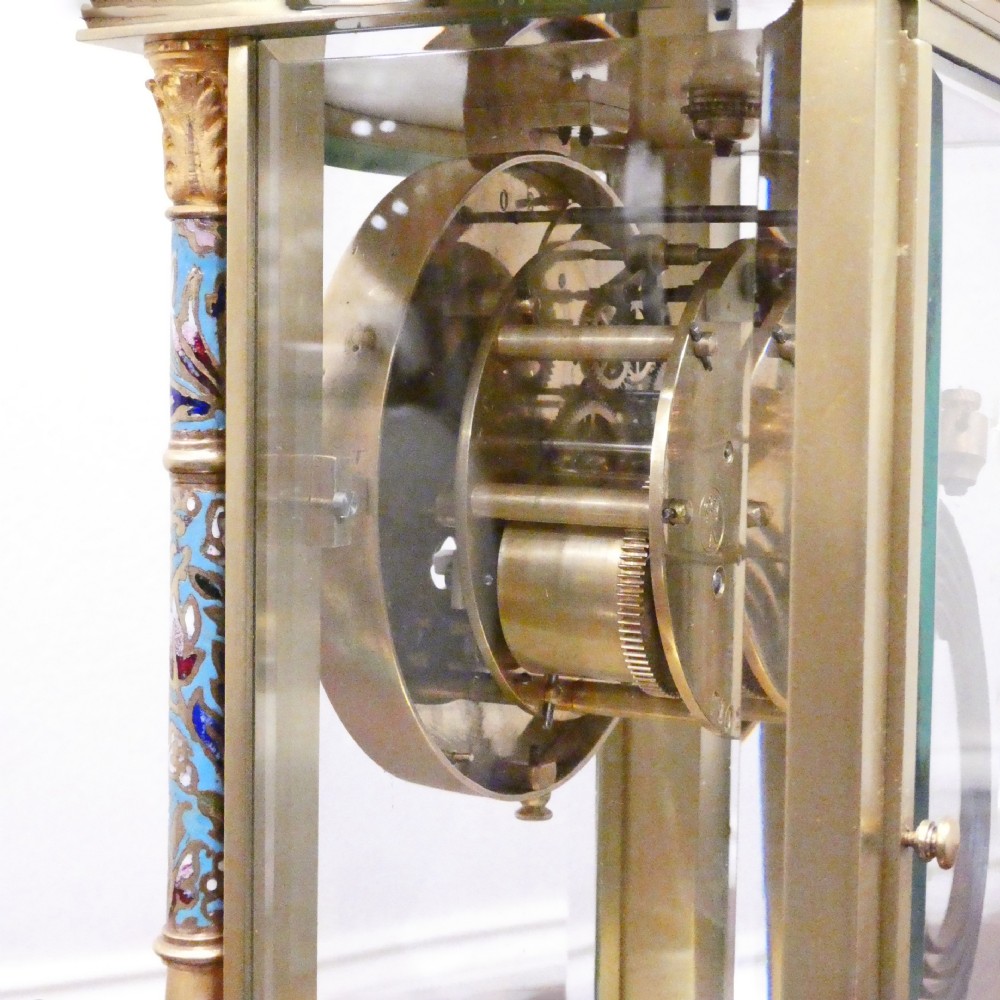 An antique French four-glass mantel clock featuring green onyx bases, champleve enamel columns, and a visible brass movement. View X