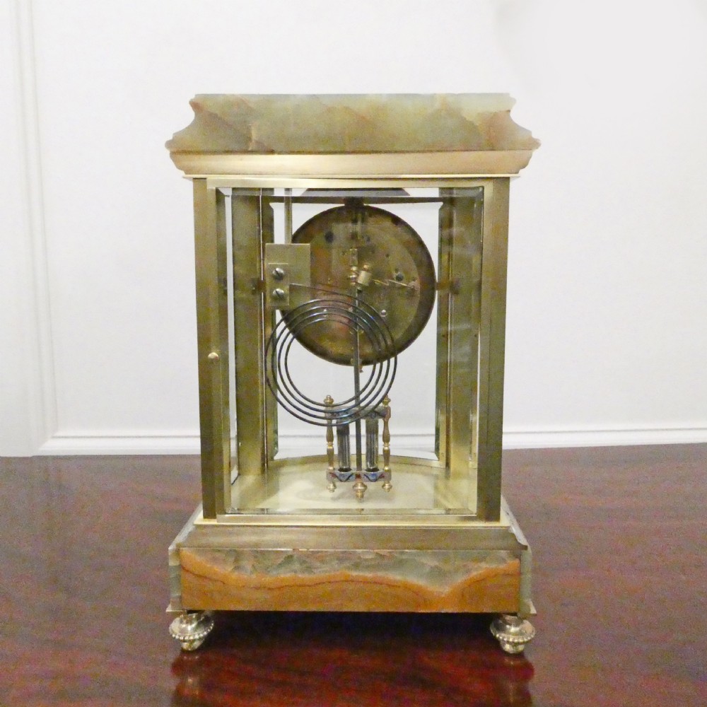 An antique French four-glass mantel clock featuring green onyx bases, champleve enamel columns, and a visible brass movement. View XI