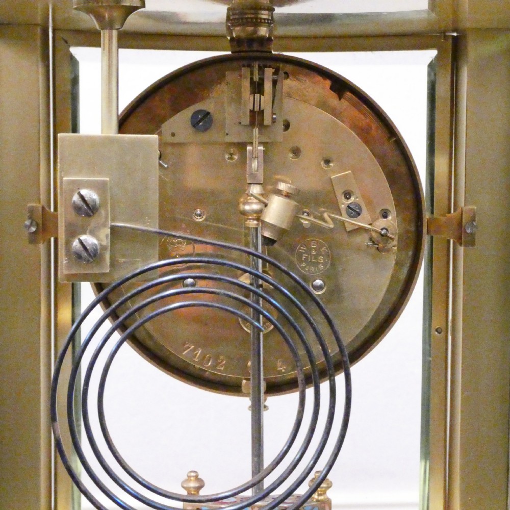 An antique French four-glass mantel clock featuring green onyx bases, champleve enamel columns, and a visible brass movement. View XII