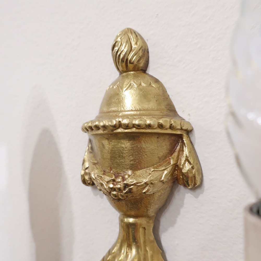A pair of French Louis XVI style gilt bronze twin arm wall lights featuring classical urn finials and ribbon relief decorations. View VIII