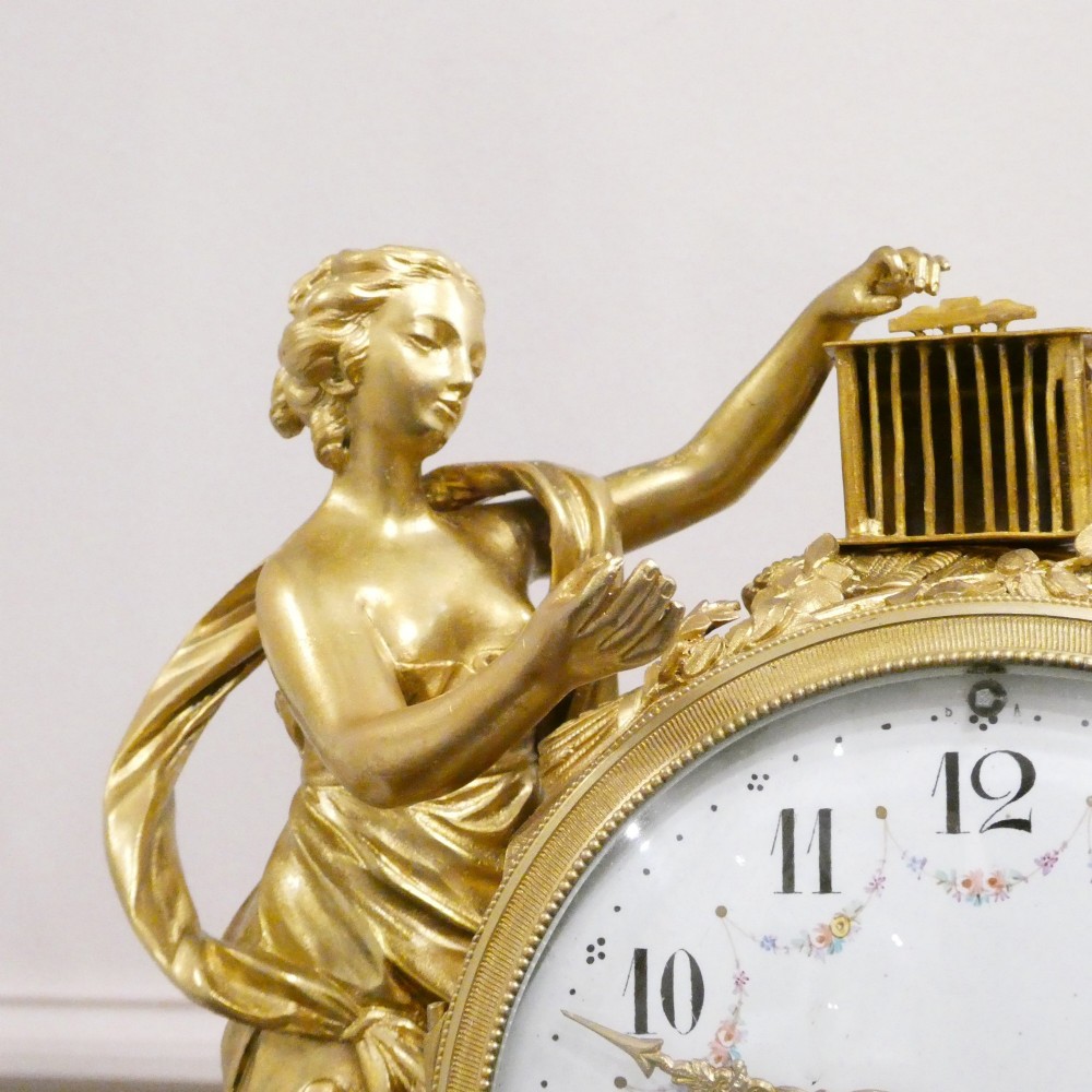 A French Louis XVI style gilt bronze and white marble mantel clock featuring classical female and winged cherub figures surrounding a white enamel dial. View III