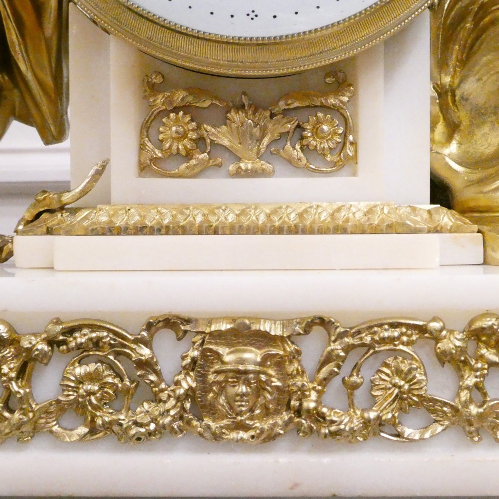 A French Louis XVI style gilt bronze and white marble mantel clock featuring classical female and winged cherub figures surrounding a white enamel dial. View VII