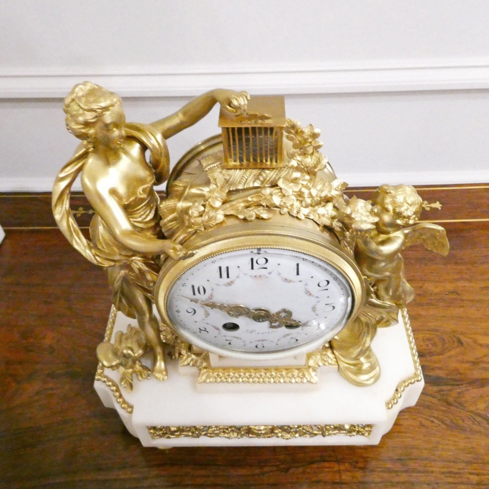 A French Louis XVI style gilt bronze and white marble mantel clock featuring classical female and winged cherub figures surrounding a white enamel dial. View XI