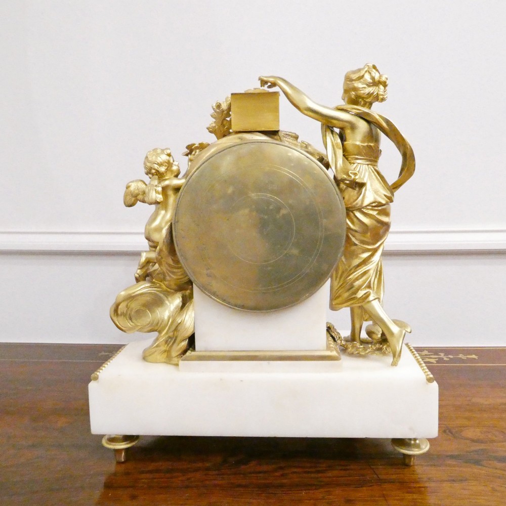 A French Louis XVI style gilt bronze and white marble mantel clock featuring classical female and winged cherub figures surrounding a white enamel dial. View XIII