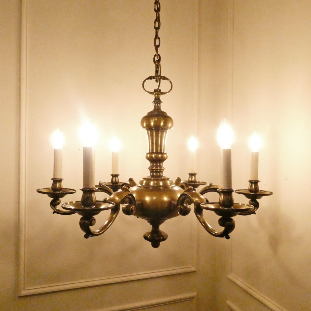 An Edwardian six-light aged brass chandelier featuring a central turned baluster shaft, scrolled arms, and candle sleeves. View II