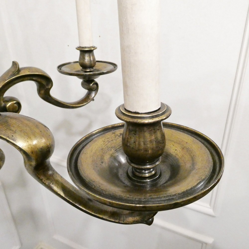 An Edwardian six-light aged brass chandelier featuring a central turned baluster shaft, scrolled arms, and candle sleeves. View V