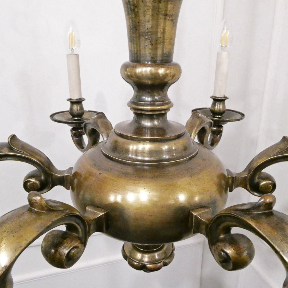 An Edwardian six-light aged brass chandelier featuring a central turned baluster shaft, scrolled arms, and candle sleeves. View VIII