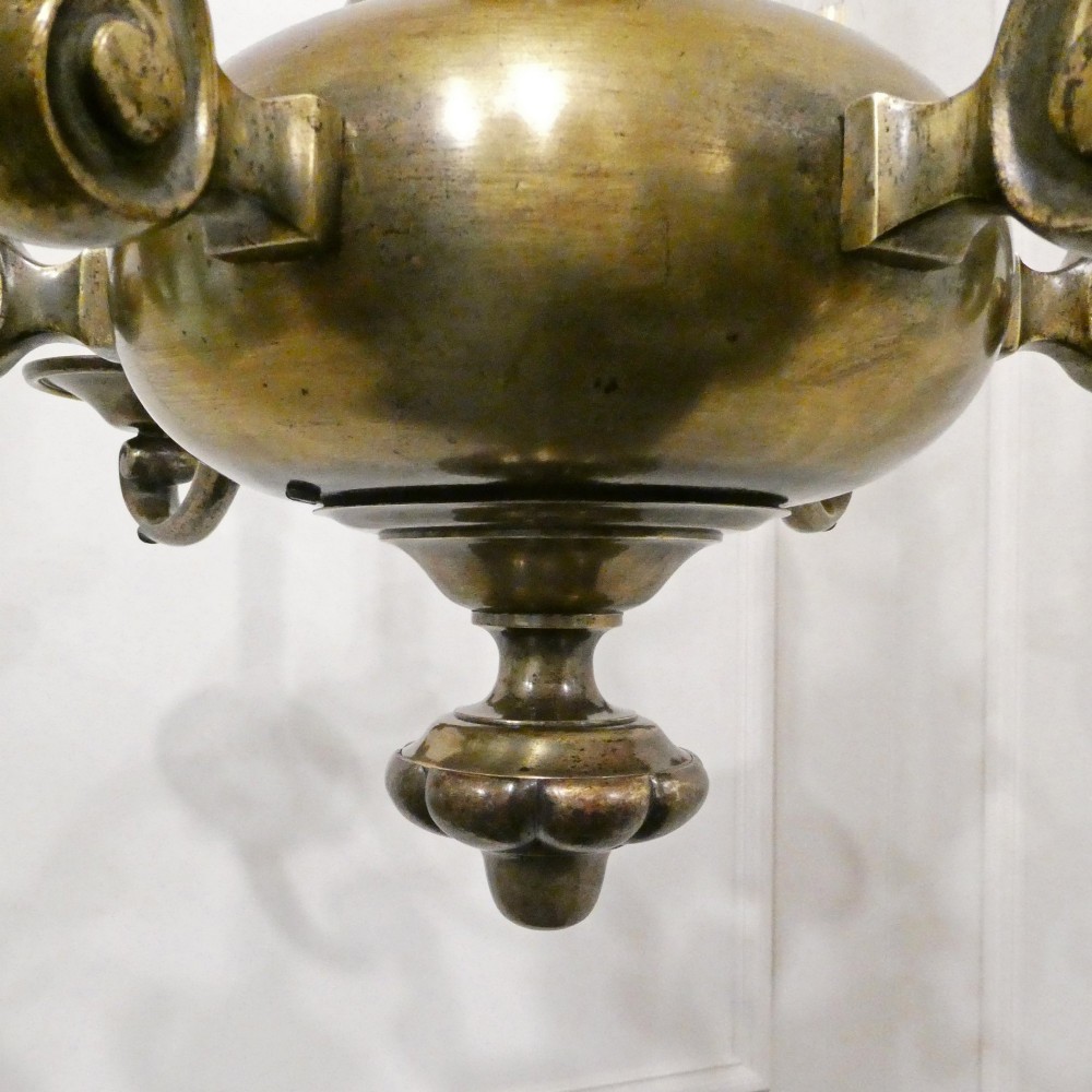 An Edwardian six-light aged brass chandelier featuring a central turned baluster shaft, scrolled arms, and candle sleeves. View XIII