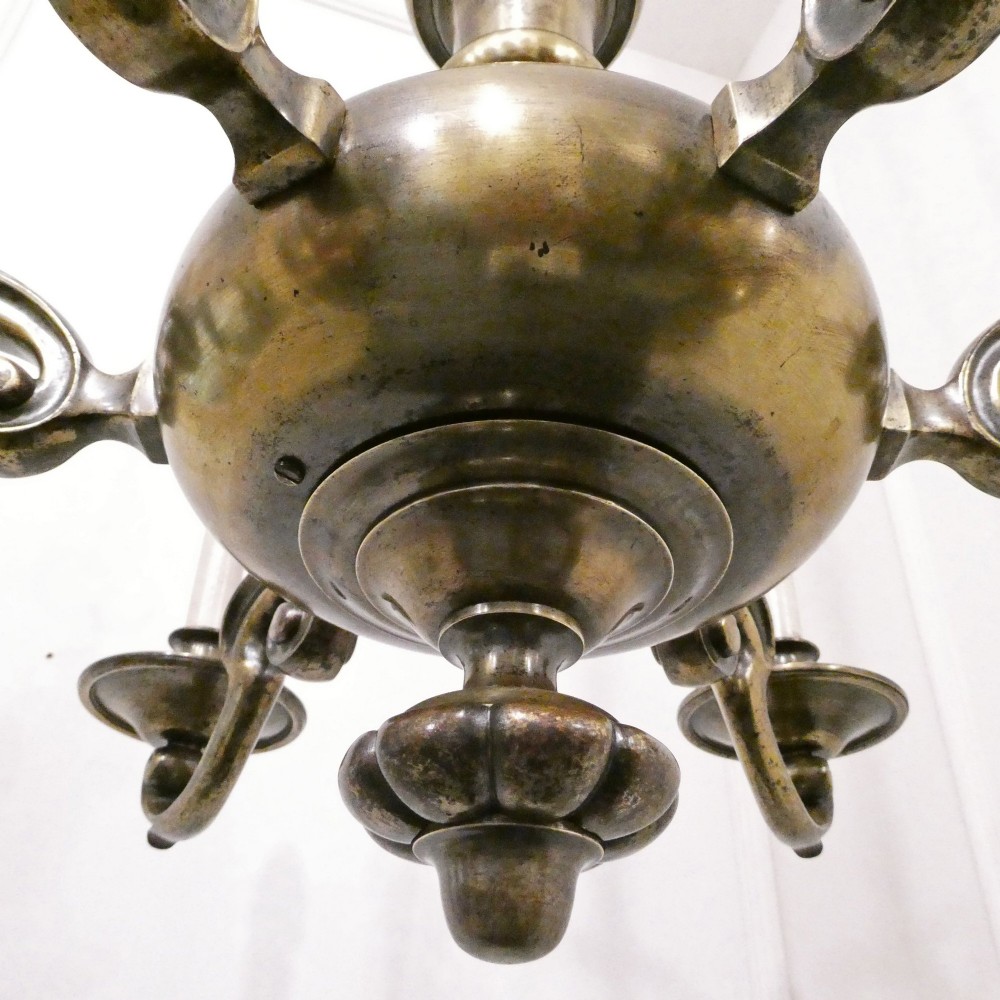 An Edwardian six-light aged brass chandelier featuring a central turned baluster shaft, scrolled arms, and candle sleeves. View XIV