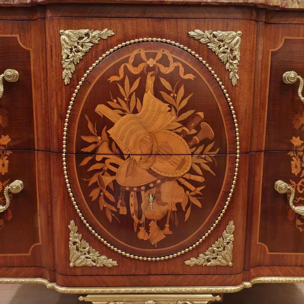 A French Louis XVI style marquetry chest of drawers featuring inlaid central medallion motifs, gilded bronze handles, tapered legs, and a fitted marble top. View II