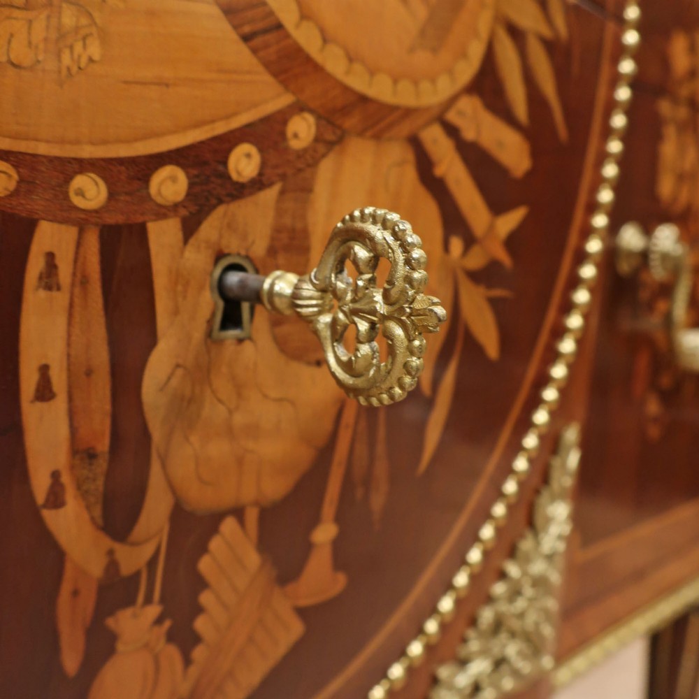 A French Louis XVI style marquetry chest of drawers featuring inlaid central medallion motifs, gilded bronze handles, tapered legs, and a fitted marble top. View IV
