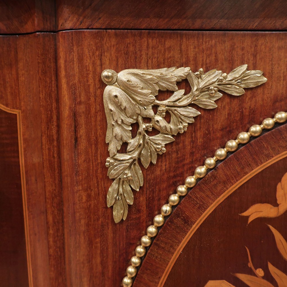 A French Louis XVI style marquetry chest of drawers featuring inlaid central medallion motifs, gilded bronze handles, tapered legs, and a fitted marble top. View V