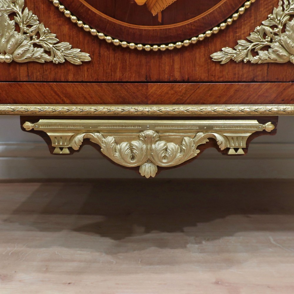 A French Louis XVI style marquetry chest of drawers featuring inlaid central medallion motifs, gilded bronze handles, tapered legs, and a fitted marble top. View IX