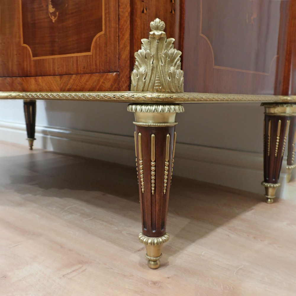 A French Louis XVI style marquetry chest of drawers featuring inlaid central medallion motifs, gilded bronze handles, tapered legs, and a fitted marble top. View X