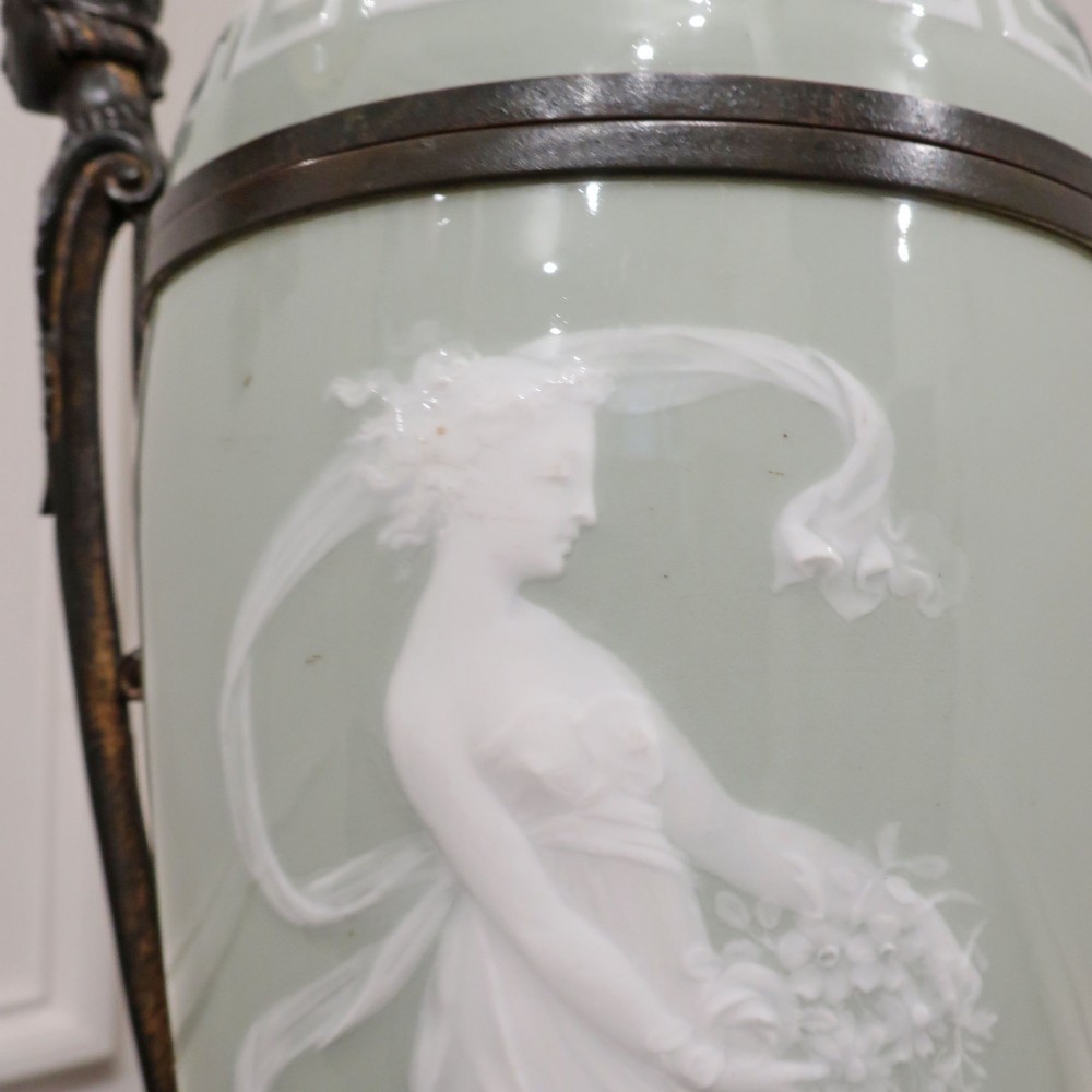 A French Neoclassical style table lamp featuring a pale green pate-sur-pate porcelain urn base, dark bronze side handles, and a pleated cream shade. View III