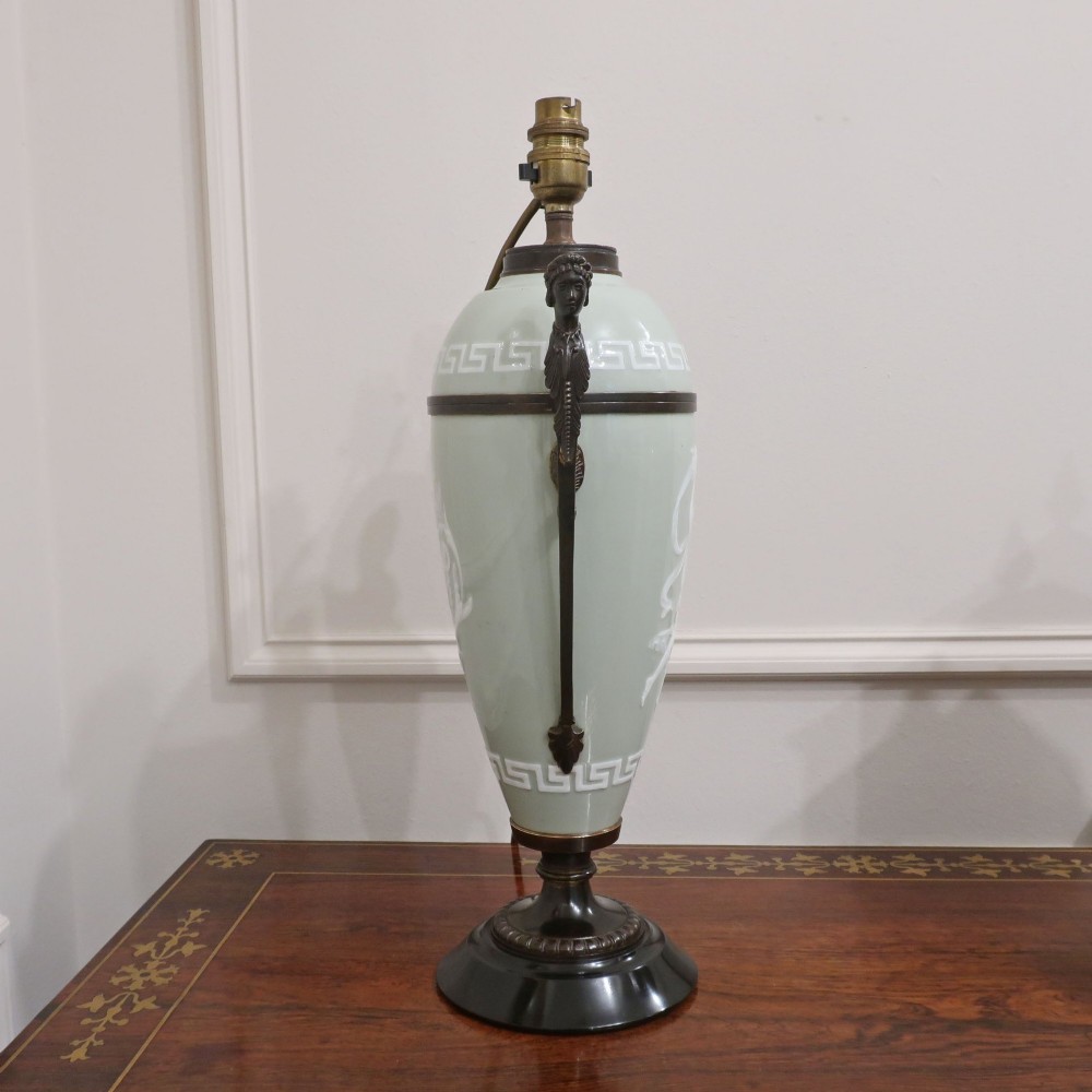 A French Neoclassical style table lamp featuring a pale green pate-sur-pate porcelain urn base, dark bronze side handles, and a pleated cream shade. View VII