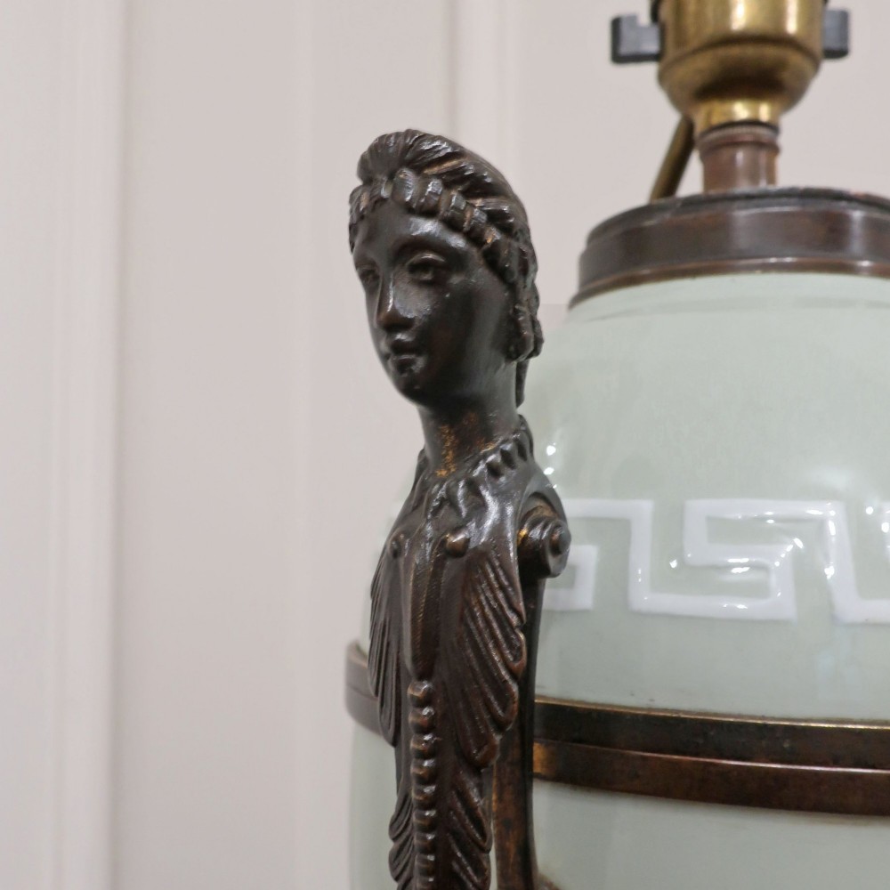 A French Neoclassical style table lamp featuring a pale green pate-sur-pate porcelain urn base, dark bronze side handles, and a pleated cream shade. View VIII