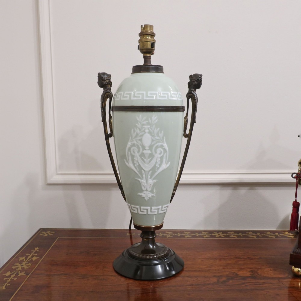 A French Neoclassical style table lamp featuring a pale green pate-sur-pate porcelain urn base, dark bronze side handles, and a pleated cream shade. View X