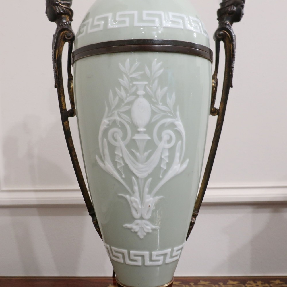 A French Neoclassical style table lamp featuring a pale green pate-sur-pate porcelain urn base, dark bronze side handles, and a pleated cream shade. View XI