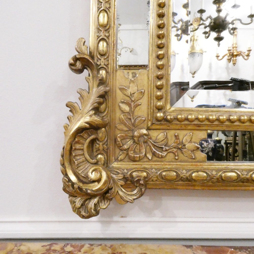 A 19th-century French Louis XVI style gilded wall mirror featuring a carved decorative crest and beaded frame border. View VIII