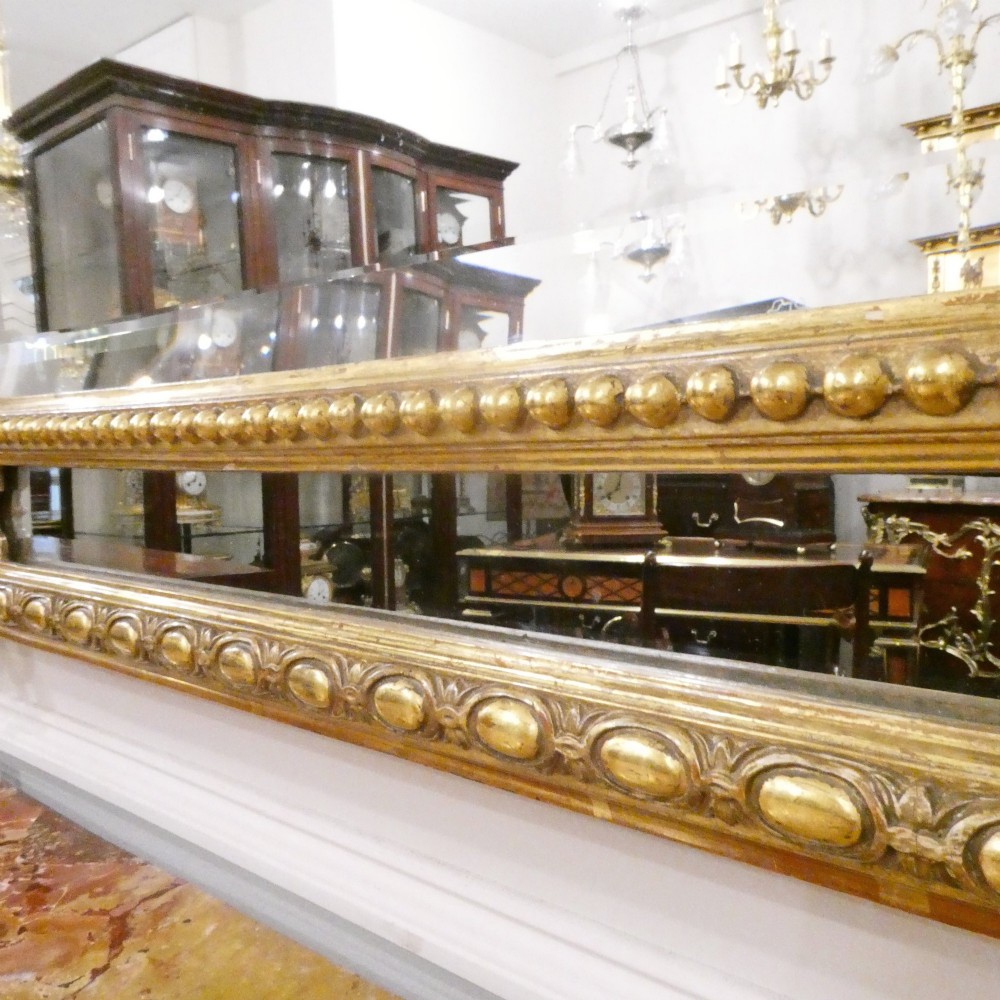 A 19th-century French Louis XVI style gilded wall mirror featuring a carved decorative crest and beaded frame border. View IX
