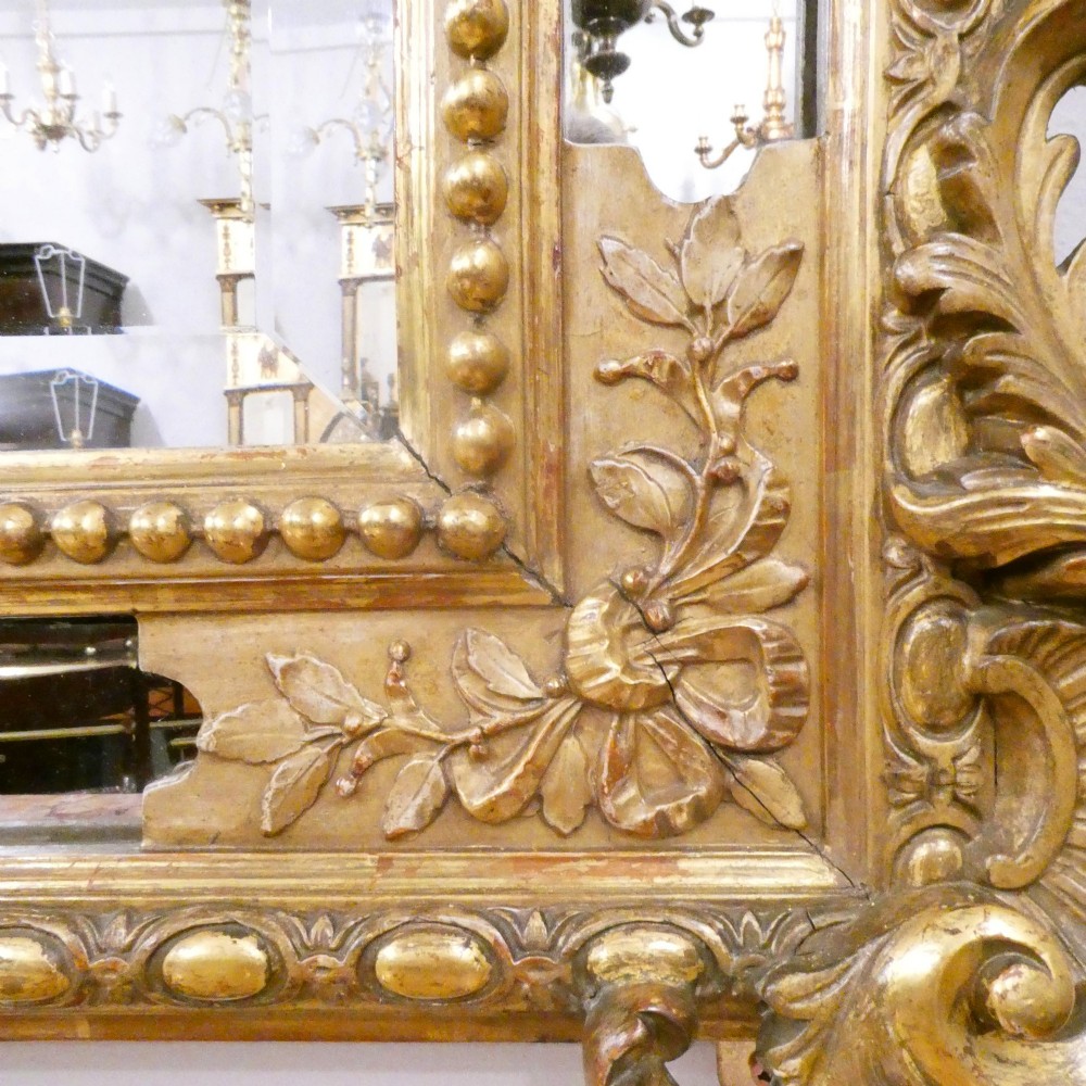 A 19th-century French Louis XVI style gilded wall mirror featuring a carved decorative crest and beaded frame border. View X