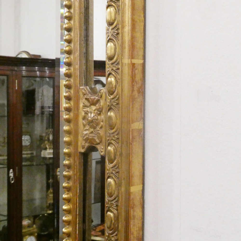 A 19th-century French Louis XVI style gilded wall mirror featuring a carved decorative crest and beaded frame border. View XIII