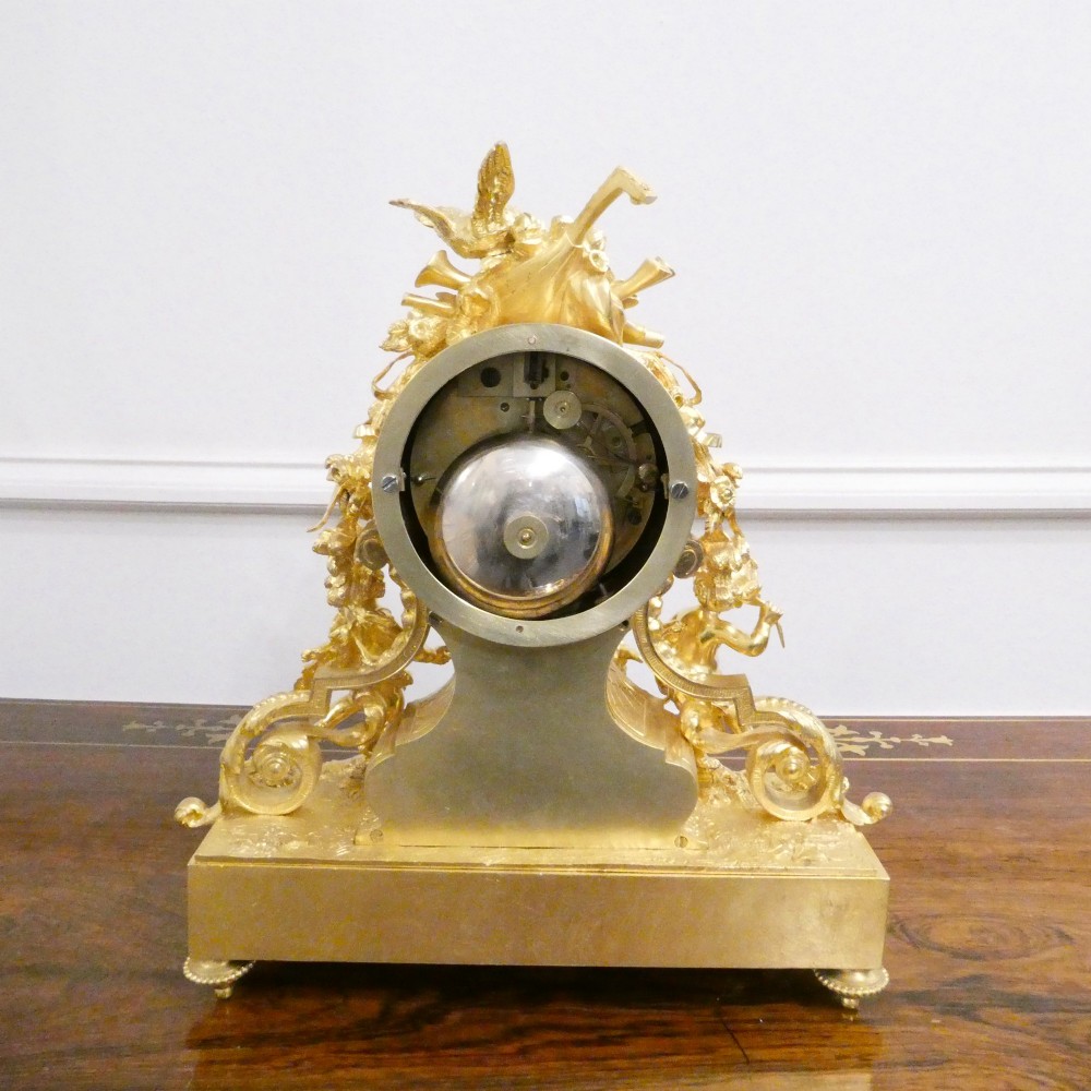 An ornate antique French gilt bronze mantel clock featuring decorative cherub figures, a recumbent goat sculpture, and blue porcelain panels painted with cherubs and floral motifs. View XII