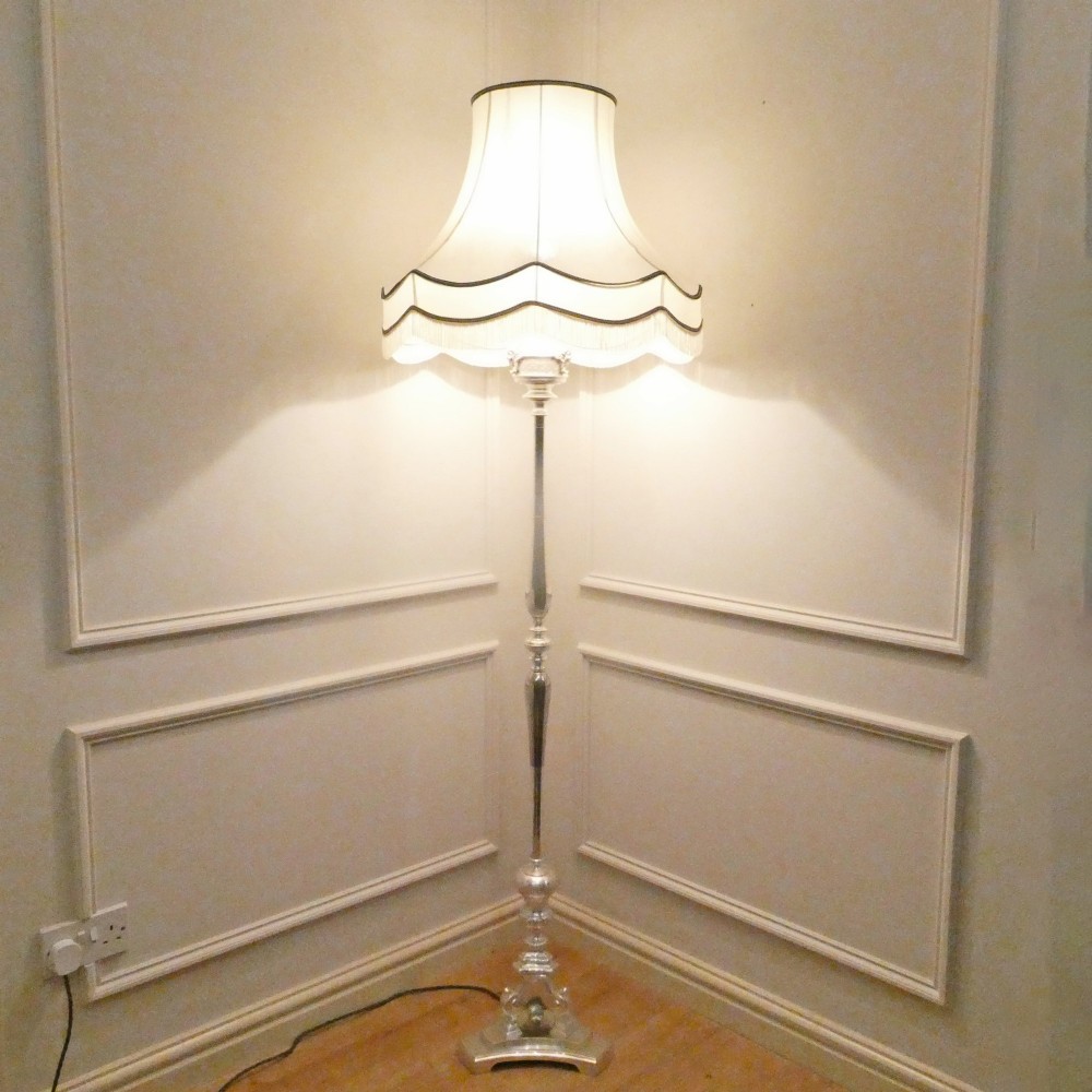 An early 20th-century silver-plated standard lamp featuring a turned column, cast base, and a cream scalloped lampshade with fringe detailing. View X