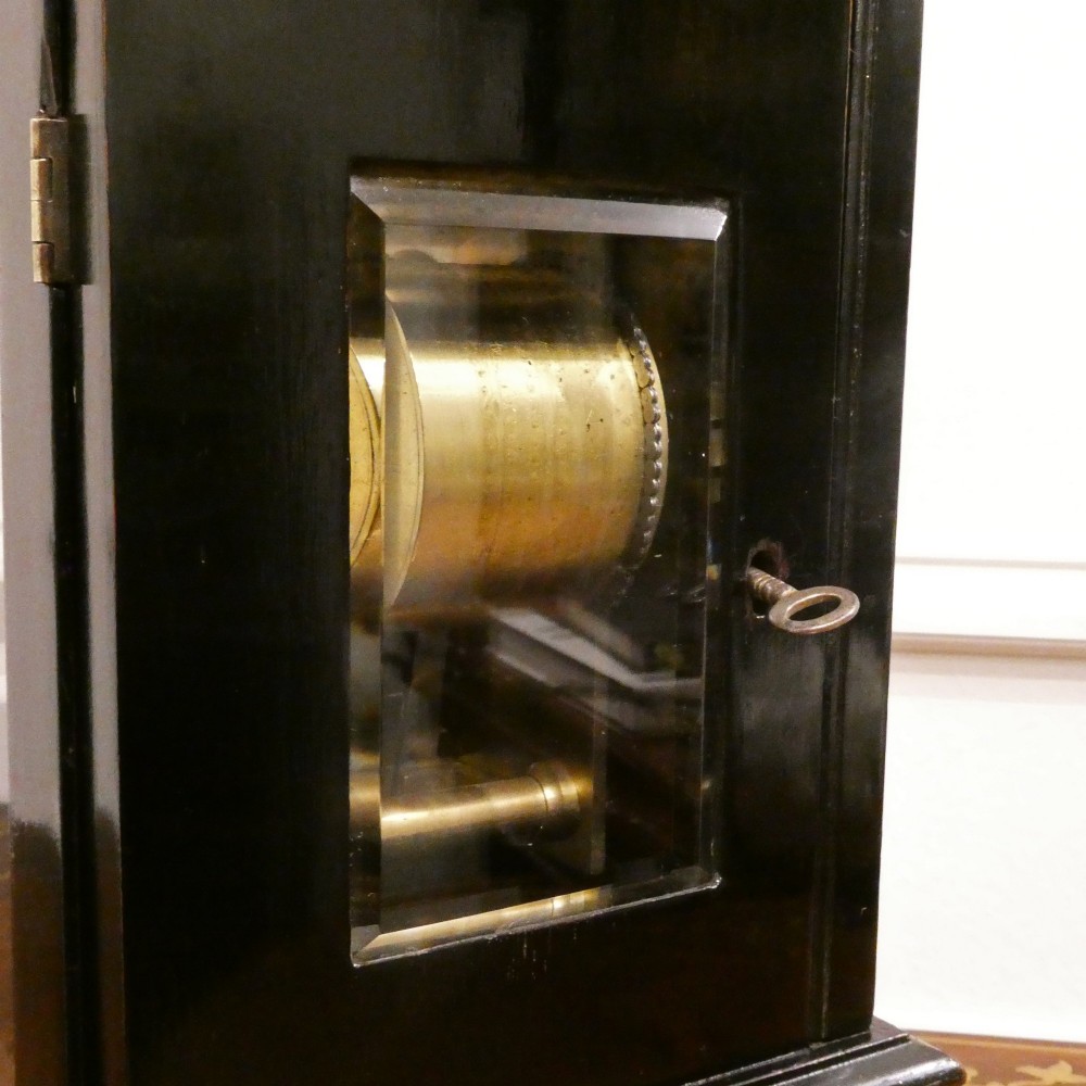 An early Victorian ebonised wooden library clock featuring a square dial with Roman numerals, side viewing apertures, and brass accents. View IX