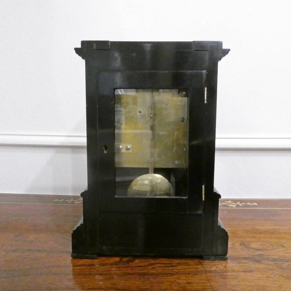 An early Victorian ebonised wooden library clock featuring a square dial with Roman numerals, side viewing apertures, and brass accents. View XI