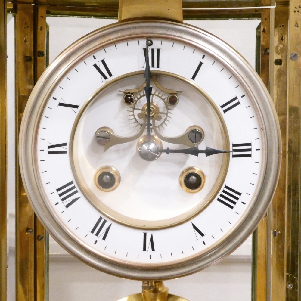 A French gilt bronze and brass four-glass mantel clock featuring an urn finial, visible pendulum mechanism, and white enamel dial with Roman numerals. View III