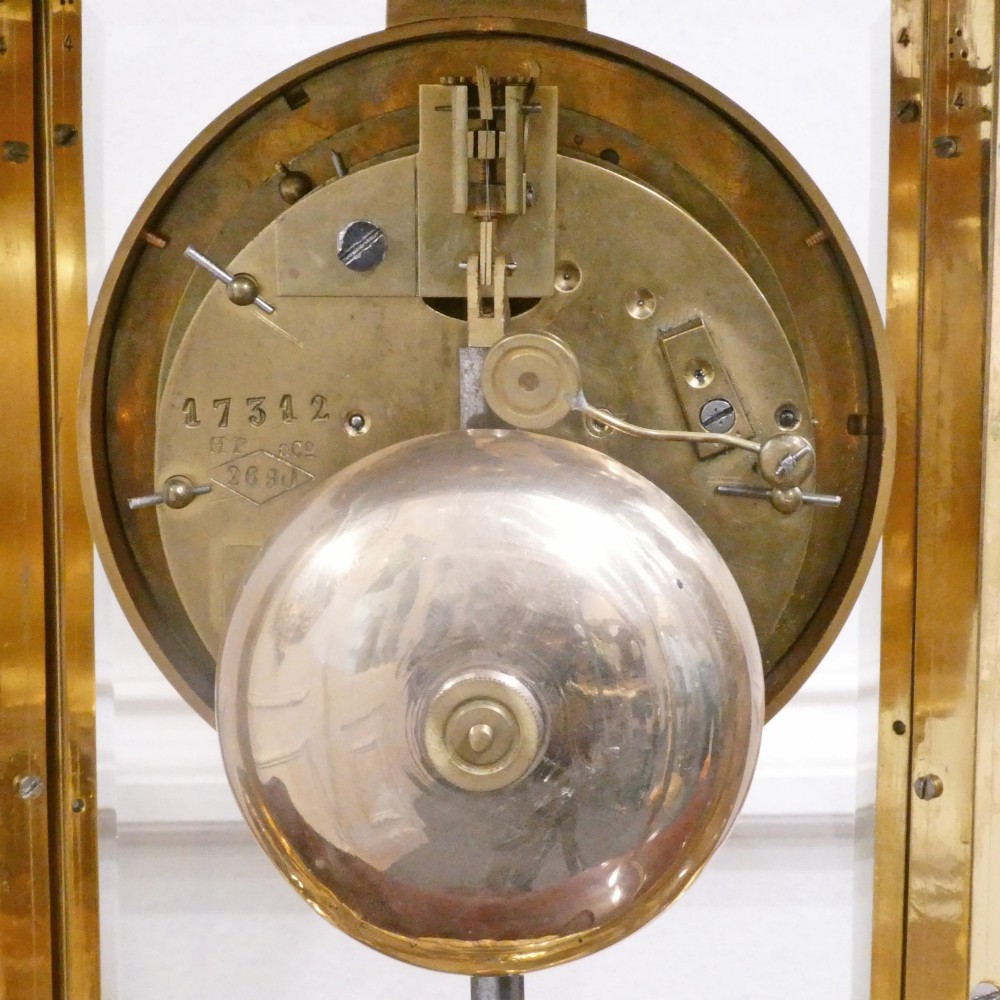 A French gilt bronze and brass four-glass mantel clock featuring an urn finial, visible pendulum mechanism, and white enamel dial with Roman numerals. View XV