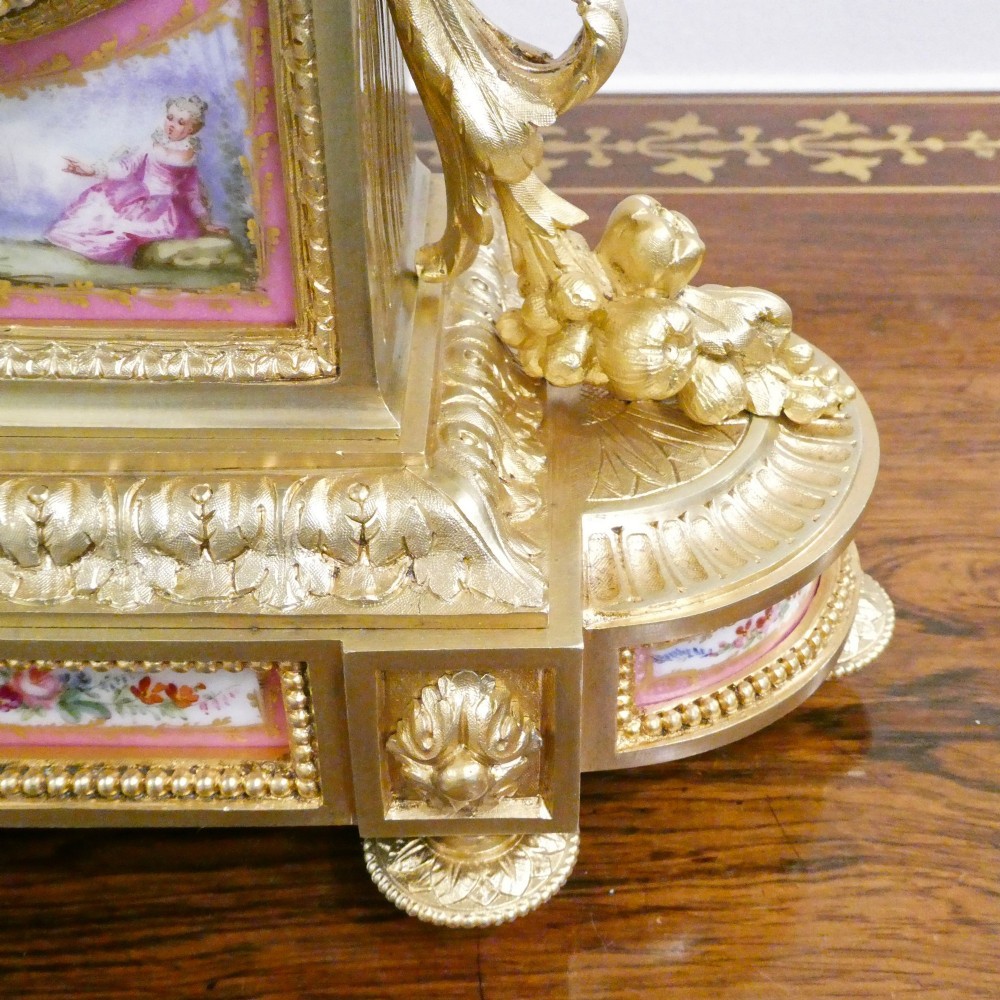 A Louis XVI style gilt bronze mantel clock featuring hand-painted pink porcelain panels and an urn-shaped finial. View V