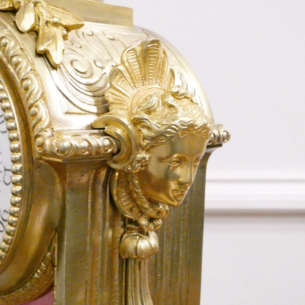 A Louis XVI style gilt bronze mantel clock featuring hand-painted pink porcelain panels and an urn-shaped finial. View X