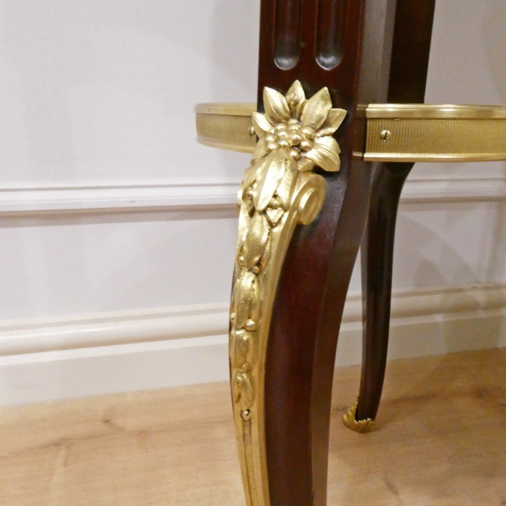 A French Louis XVI style kidney-shaped mahogany side table featuring a marble top, pierced brass gallery, lower undertier, and elaborate gilt-bronze mounts. View VII