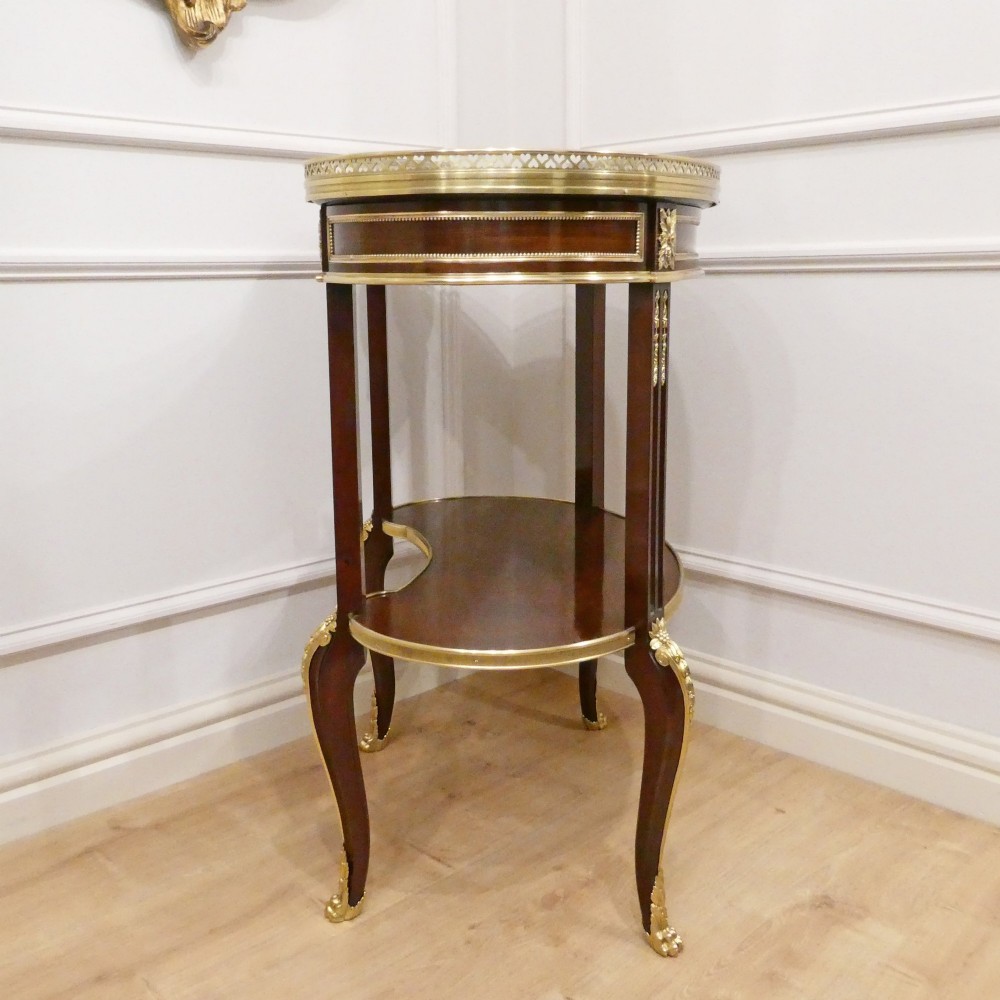 A French Louis XVI style kidney-shaped mahogany side table featuring a marble top, pierced brass gallery, lower undertier, and elaborate gilt-bronze mounts. View IX