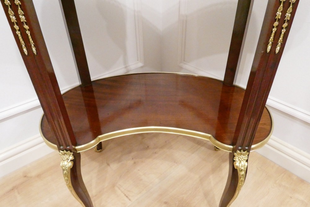 A French Louis XVI style kidney-shaped mahogany side table featuring a marble top, pierced brass gallery, lower undertier, and elaborate gilt-bronze mounts. View X