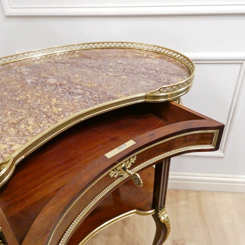 A French Louis XVI style kidney-shaped mahogany side table featuring a marble top, pierced brass gallery, lower undertier, and elaborate gilt-bronze mounts. View XI