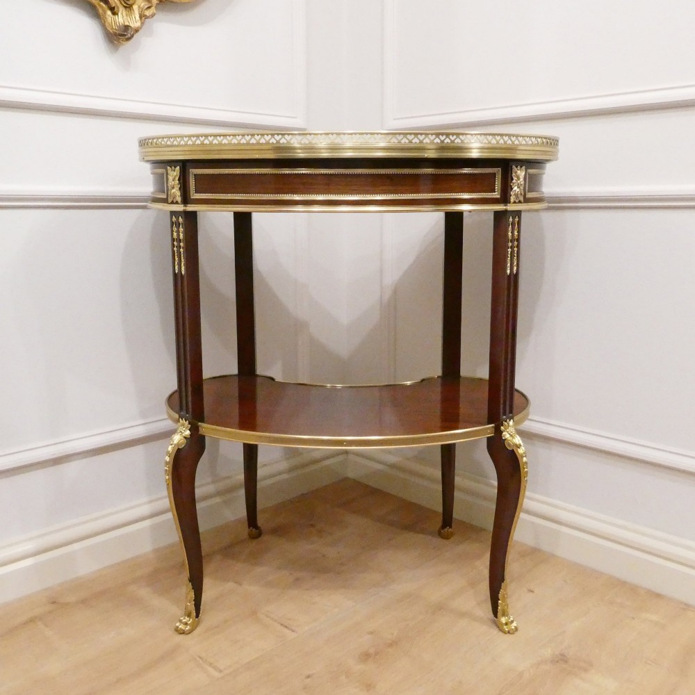 A French Louis XVI style kidney-shaped mahogany side table featuring a marble top, pierced brass gallery, lower undertier, and elaborate gilt-bronze mounts. View XII