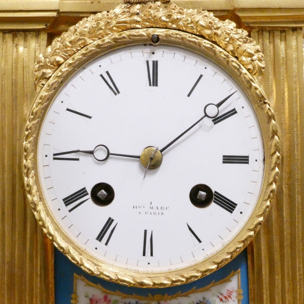 A French Louis XVI style gilt bronze mantel clock featuring a top urn finial, fluted side columns, and hand-painted blue porcelain panels around a white enamel dial. View III