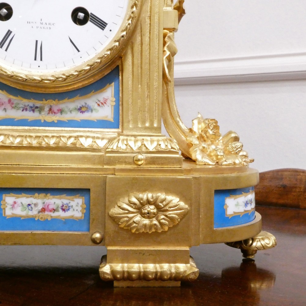 A French Louis XVI style gilt bronze mantel clock featuring a top urn finial, fluted side columns, and hand-painted blue porcelain panels around a white enamel dial. View IV