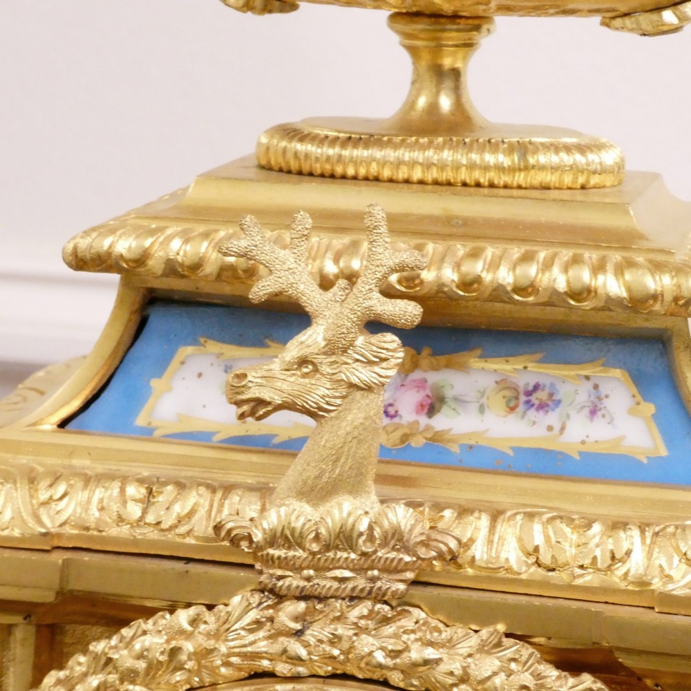 A French Louis XVI style gilt bronze mantel clock featuring a top urn finial, fluted side columns, and hand-painted blue porcelain panels around a white enamel dial. View VIII