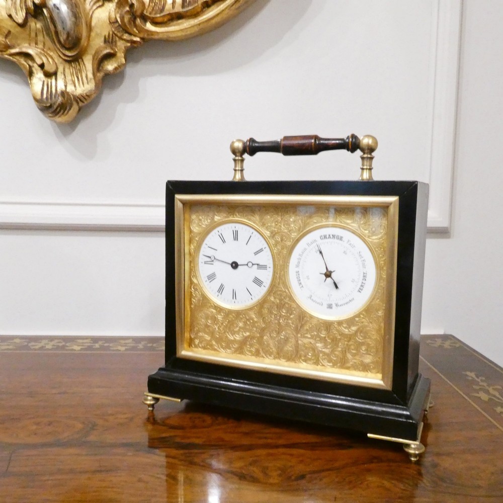 An Edwardian rectangular ebonised wooden mantel clock and barometer unit with twin white circular dials set into a scroll-engraved brass plate. View II