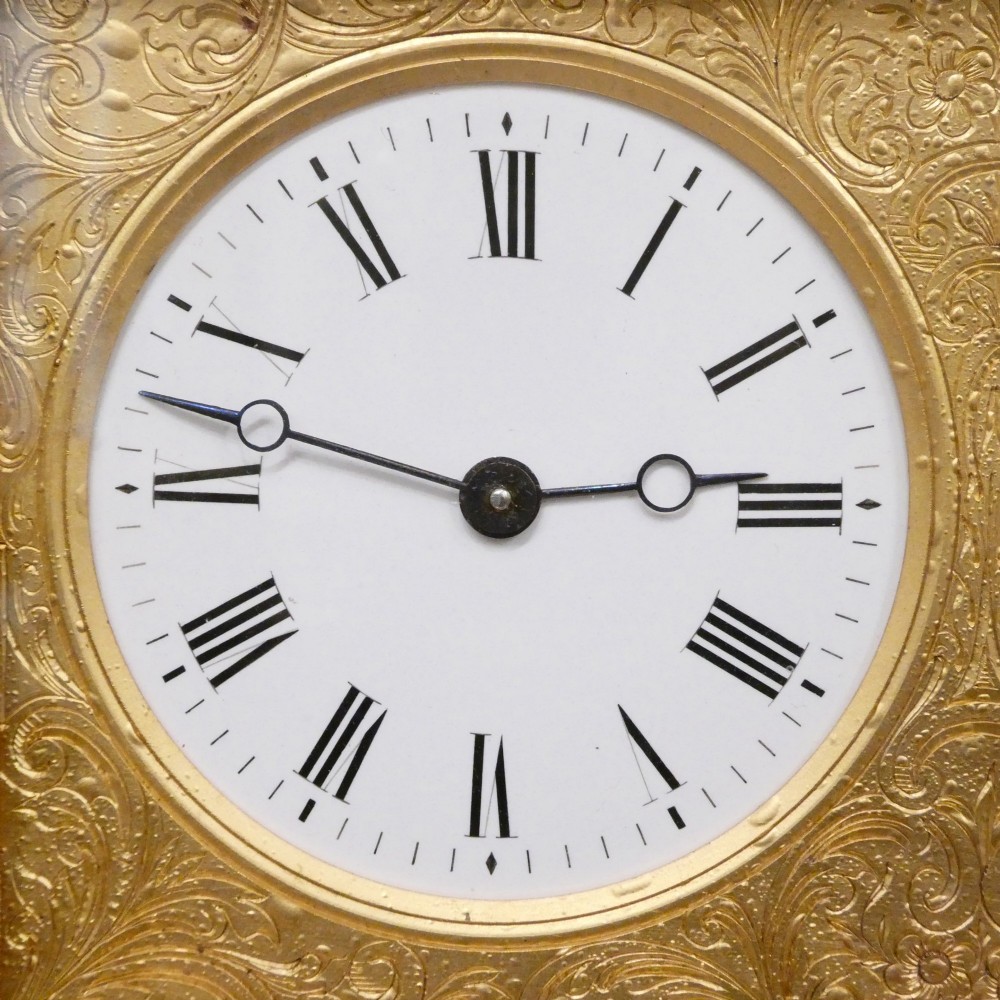 An Edwardian rectangular ebonised wooden mantel clock and barometer unit with twin white circular dials set into a scroll-engraved brass plate. View III